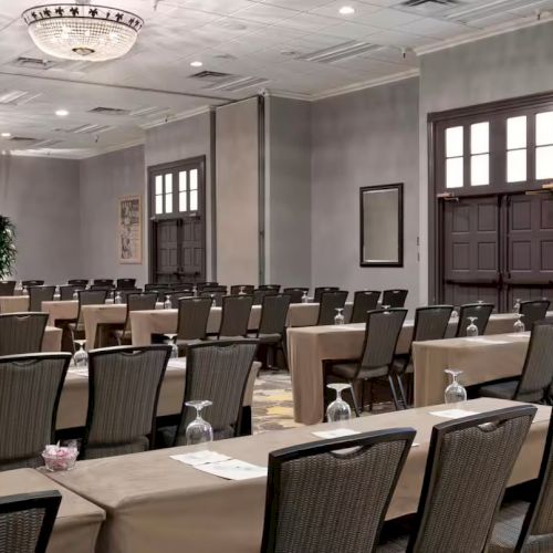 The image shows a conference room setup with rows of tables and chairs facing a podium, ready for a presentation or meeting.